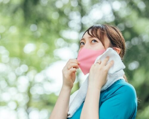 汗を拭うマスク姿の女性